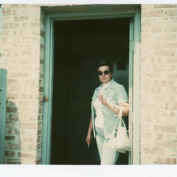 A woman in sunglasses and a checkered outfit stands in a doorway, holding keys and a purse.