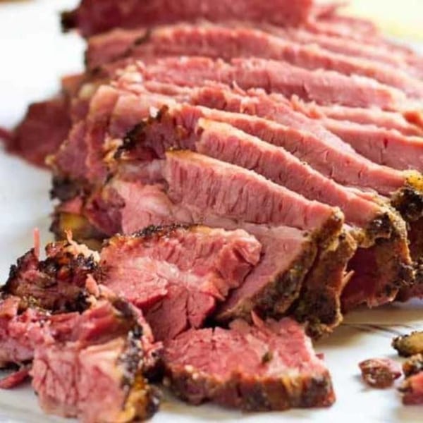 Close-up of thinly sliced, juicy corned beef with a dark, seasoned crust from Helfeld's Delicatessen.