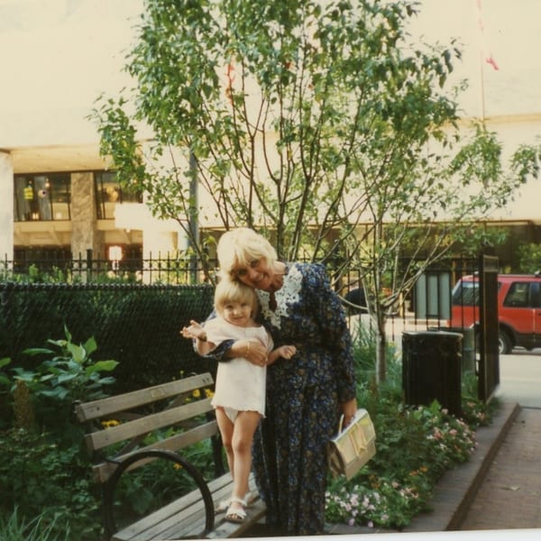 A woman and a young child pose together on a sunny day outside Helfeld's Delicatessen.