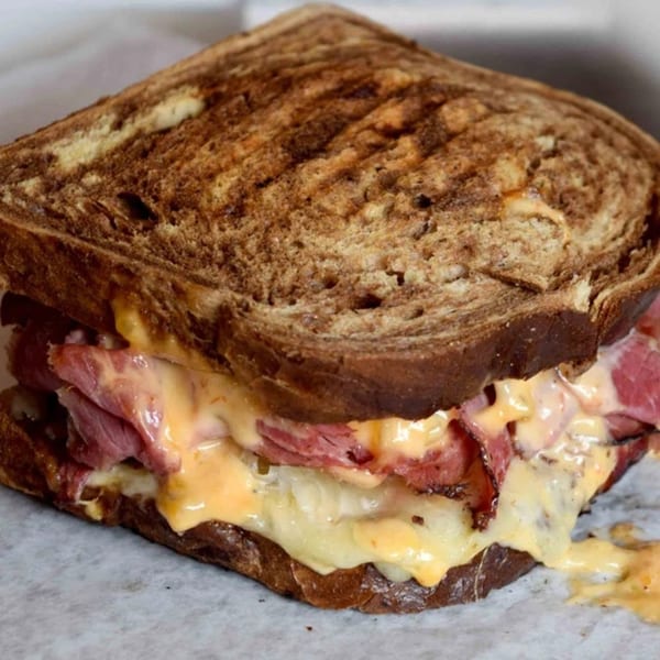 Helfeld's Delicatessen & Catering's grilled pastrami sandwich with melted cheese and sauerkraut on rye bread.